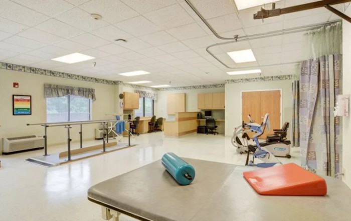 A clean and well-equipped physical therapy room with exercise equipment and workstations.
