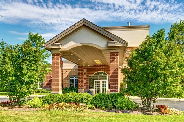 A brick building entrance with columns and well-maintained landscaping.