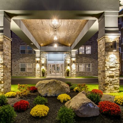 A well-lit building entrance with stone facade and vibrant landscaping.