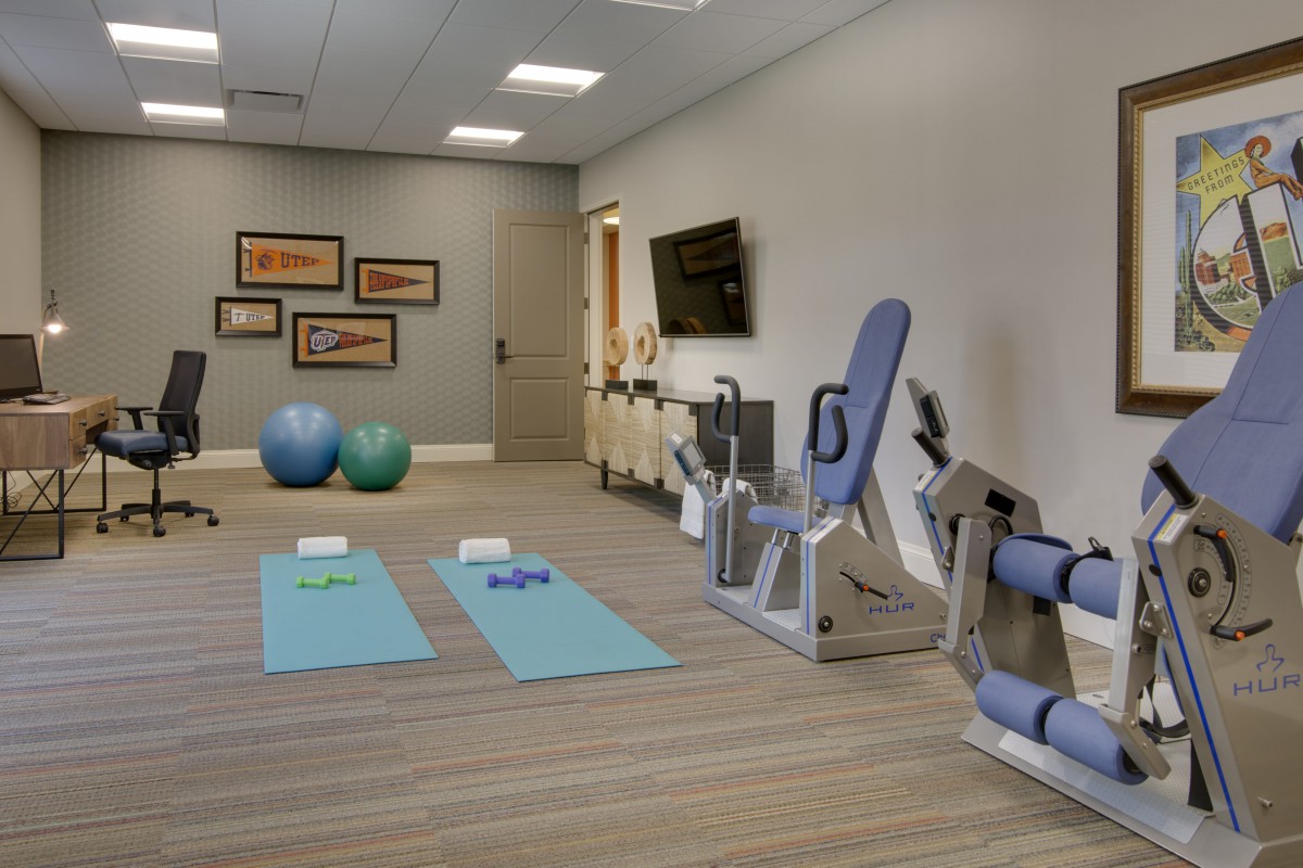 A well-equipped exercise room featuring yoga mats, stability balls, and fitness machines.