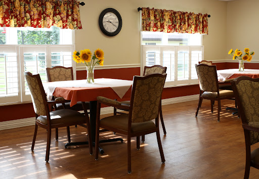 A bright and inviting dining room featuring a table adorned with sunflowers, surrounded by comfortable chairs.