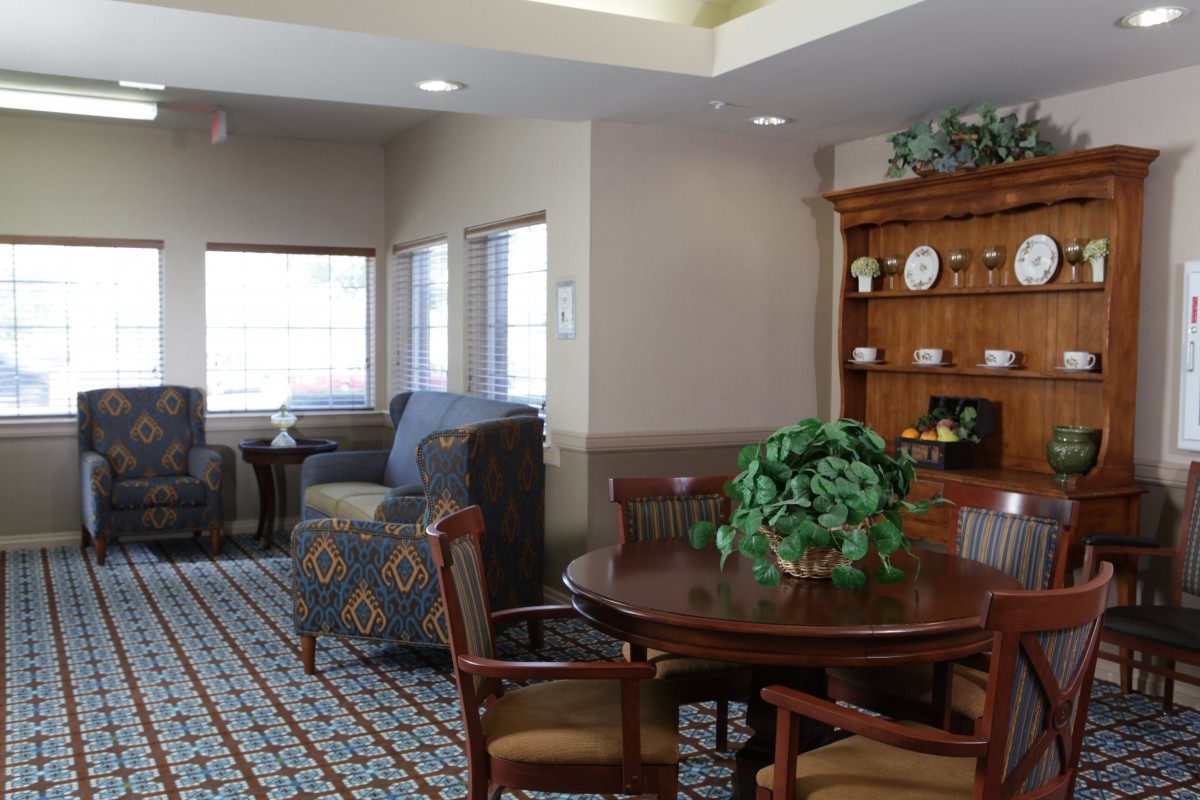 A cozy living room featuring a round table with chairs, a comfortable seating area, and decorative shelves.