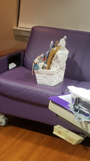 A cozy hospital corner featuring a purple chair with a basket of craft supplies.