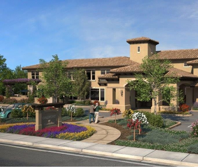 A residential building with well-maintained landscaping, featuring a garden, trees, and flowers.