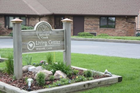 A welcoming sign for a living center surrounded by a landscaped garden.