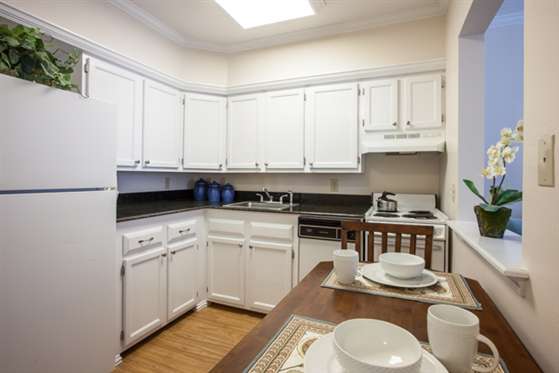 A modern kitchen with white cabinets and a small dining area.