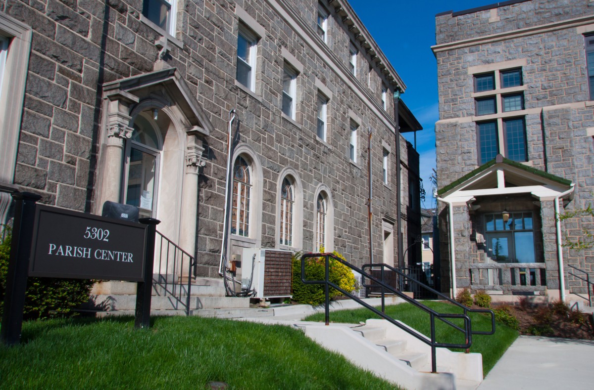 A historic stone building with arched windows and a grassy lawn under a clear blue sky.
