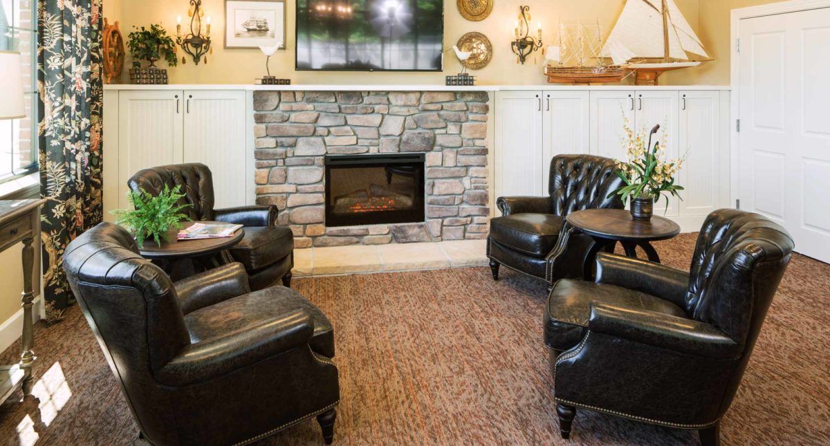 A cozy living room with a stone fireplace, leather chairs, and warm decor.