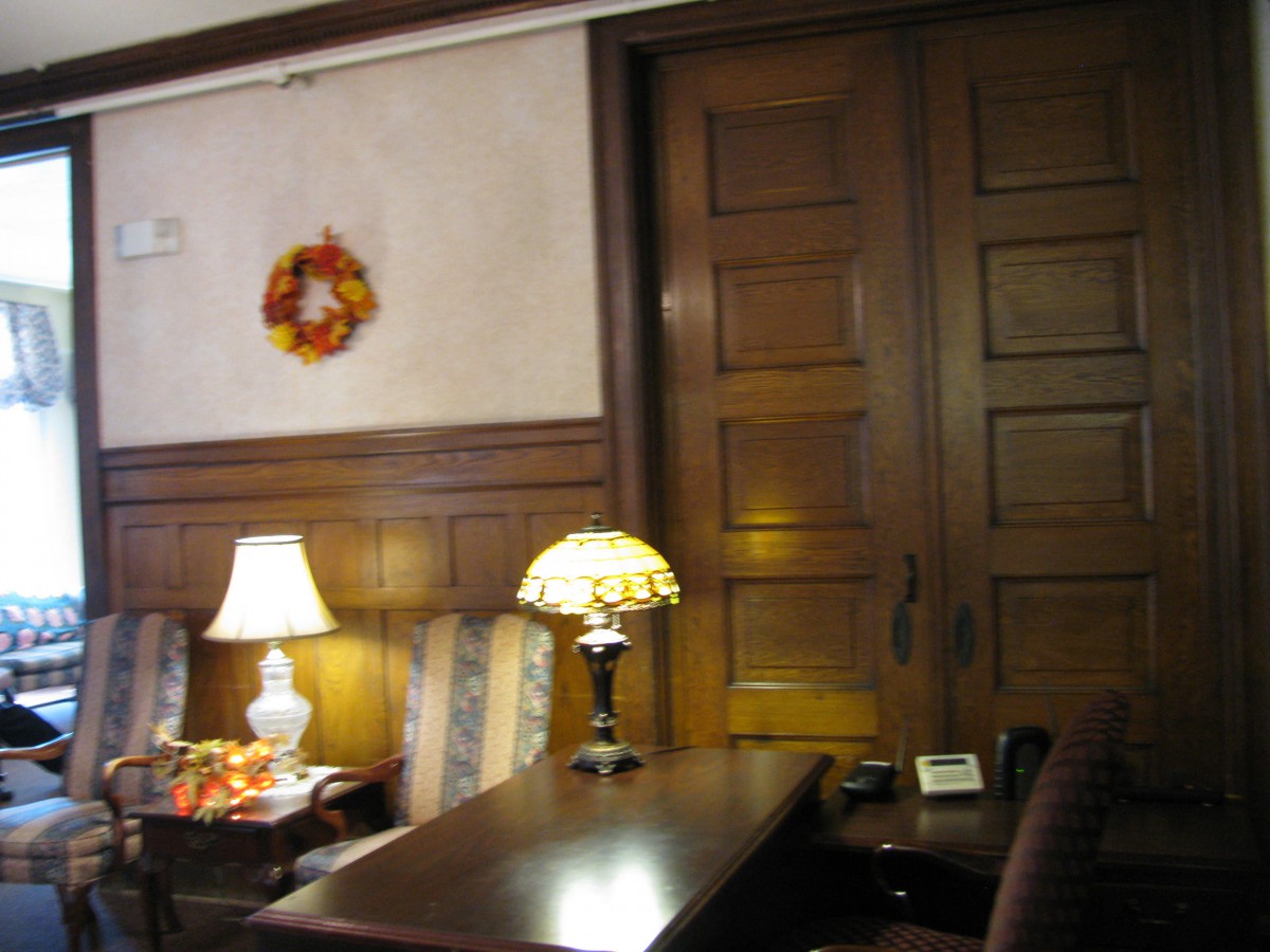 A cozy interior room with wooden doors, a table lamp, and autumn decorations.