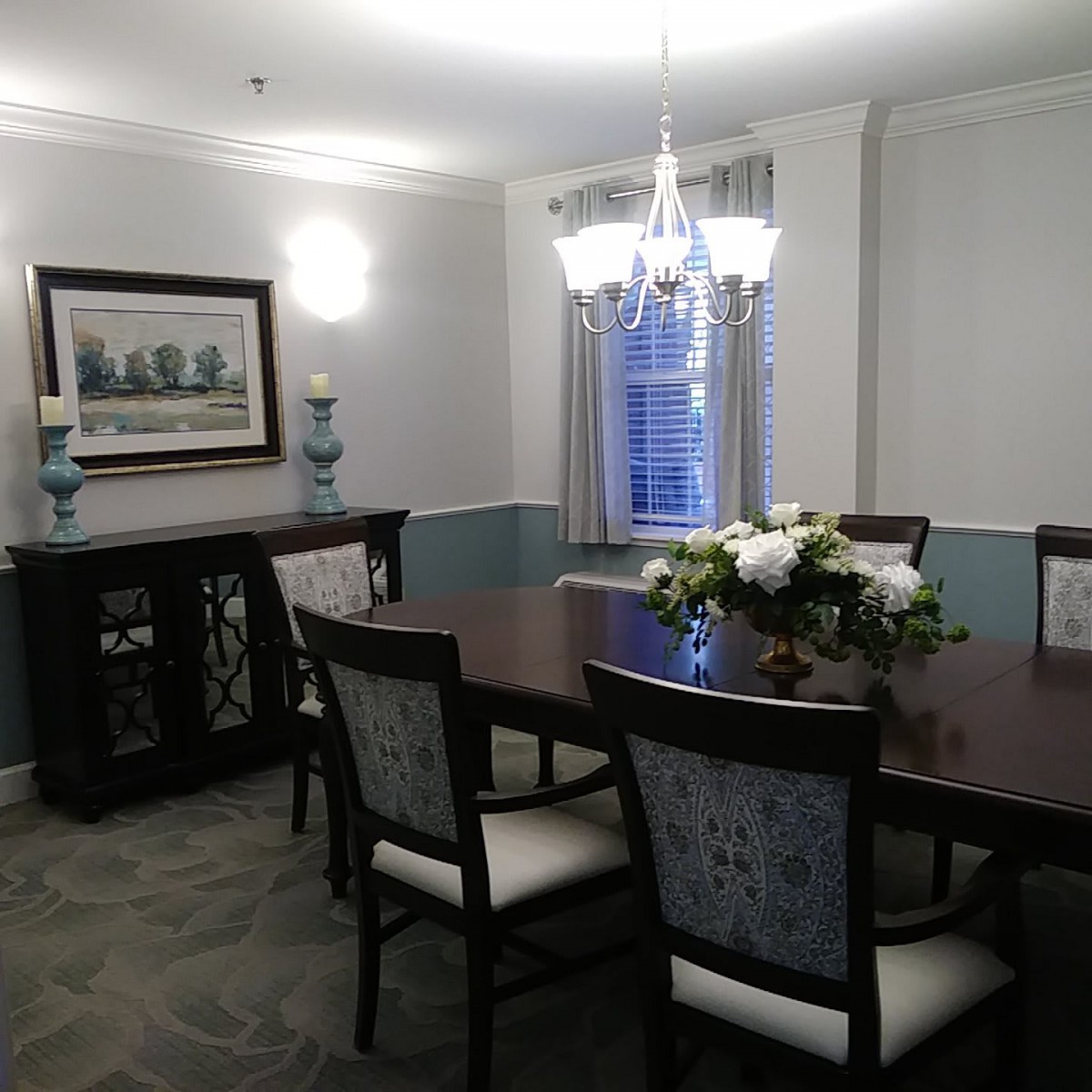 A stylish dining room with a central table, chairs, and elegant decor.