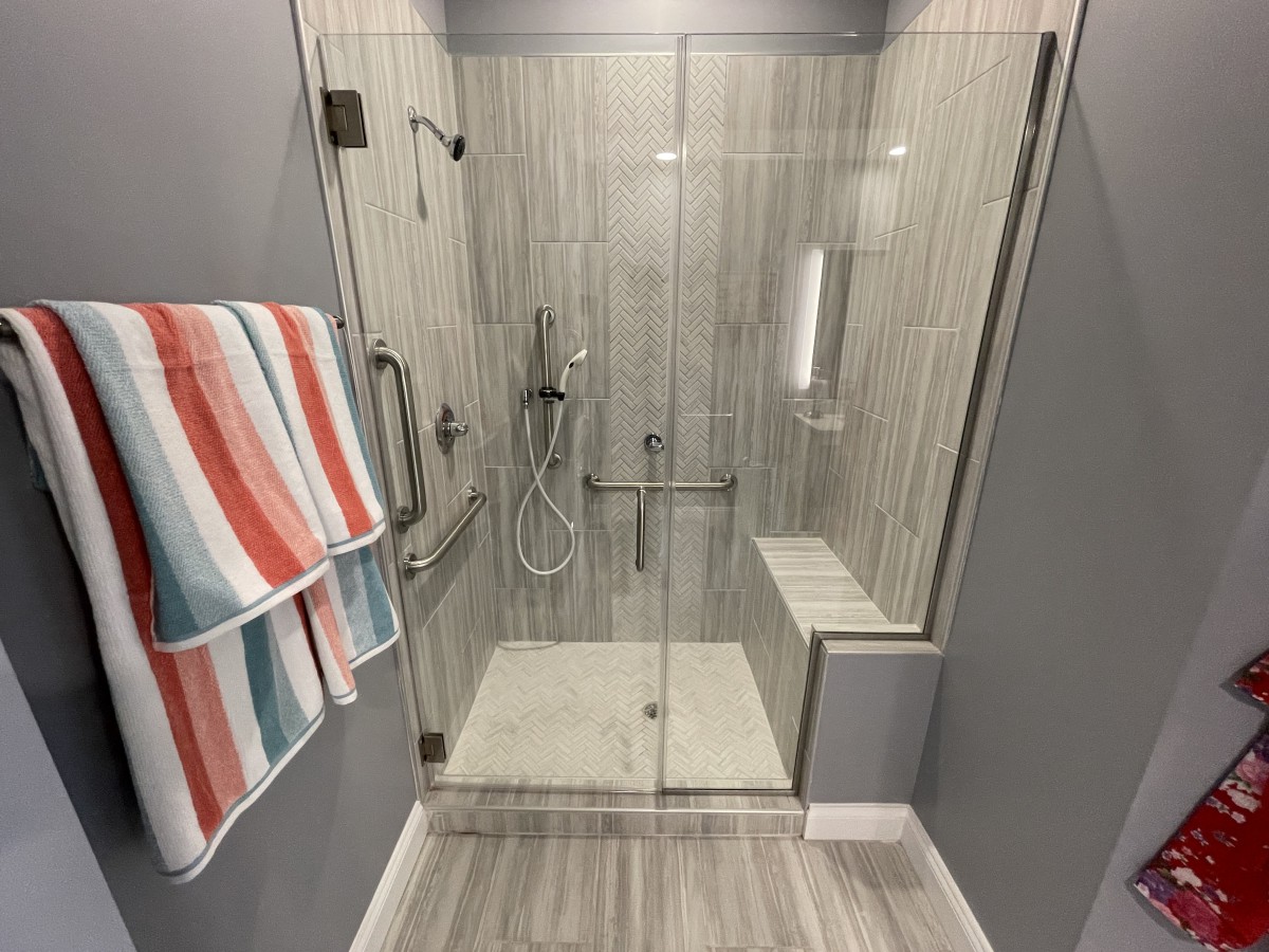A modern bathroom shower with glass doors and striped towels.