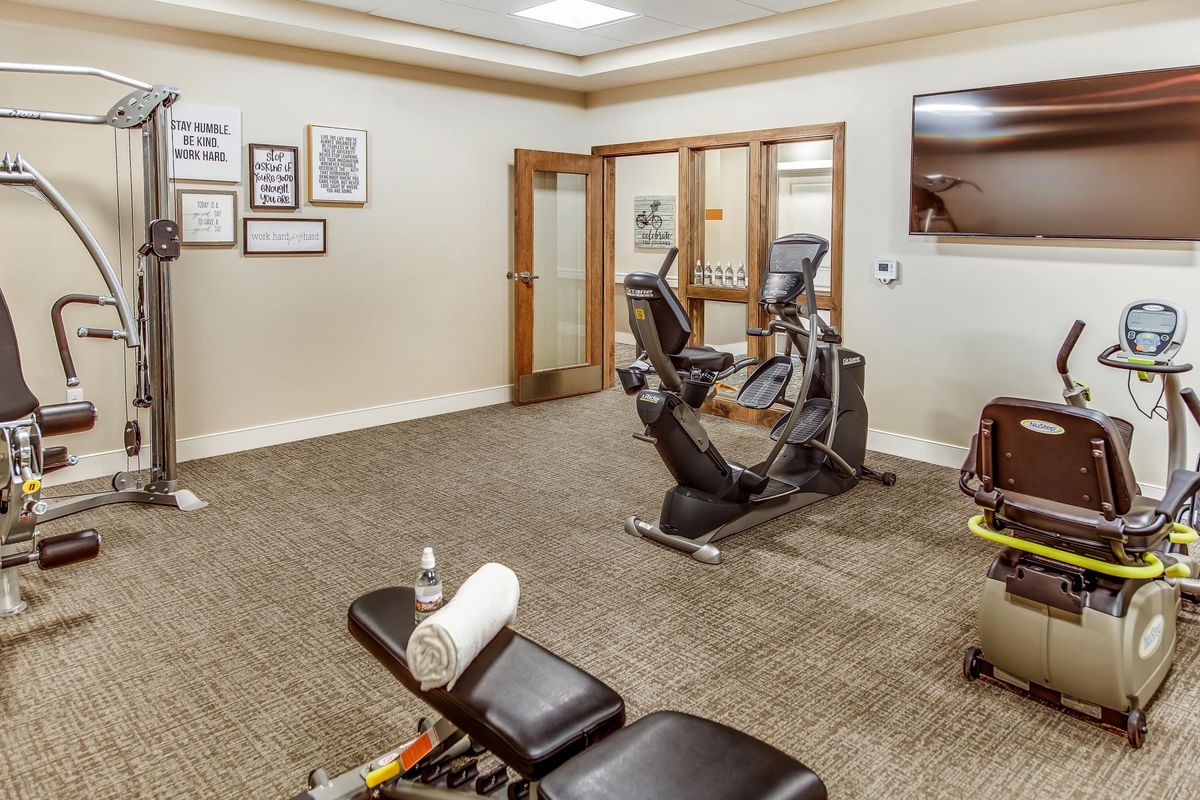A small gym with a stationary bike, weights, and a workout bench.
