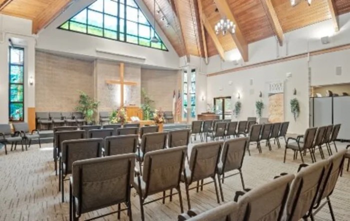 The interior of a church featuring rows of pews with a prominent cross at the front.