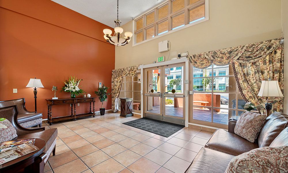 A spacious lobby with a chandelier, decorative plants, and large windows.