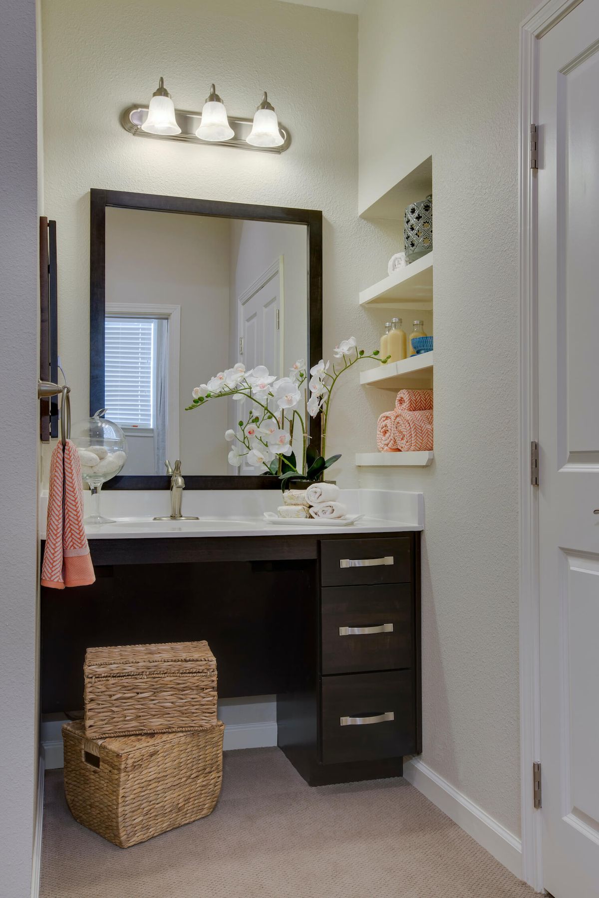 A neatly organized bathroom vanity with a large mirror, open shelves, and decorative accents.