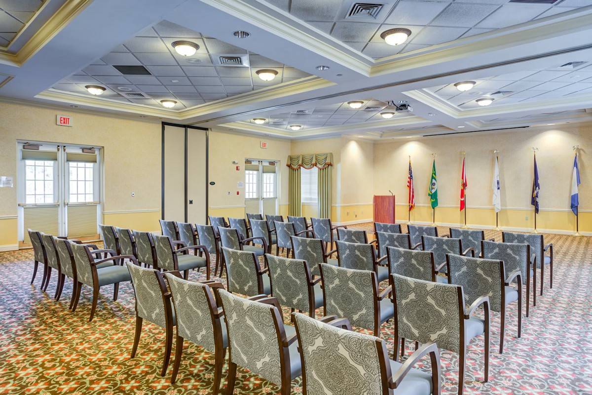 A conference room with rows of chairs and flags displayed at the front.