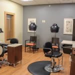 A modern salon interior with styling stations and hair dryers.
