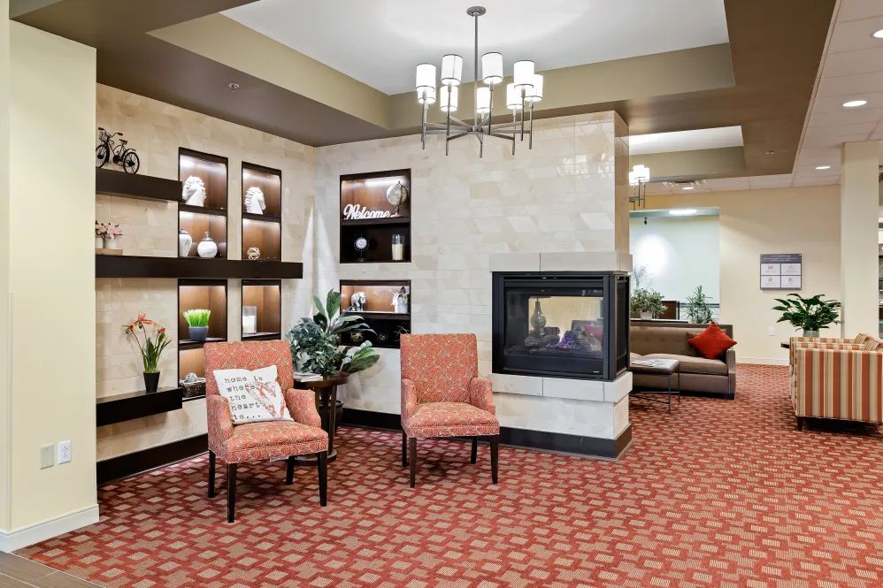 A cozy lobby area featuring a fireplace, comfortable chairs, and stylish lighting.