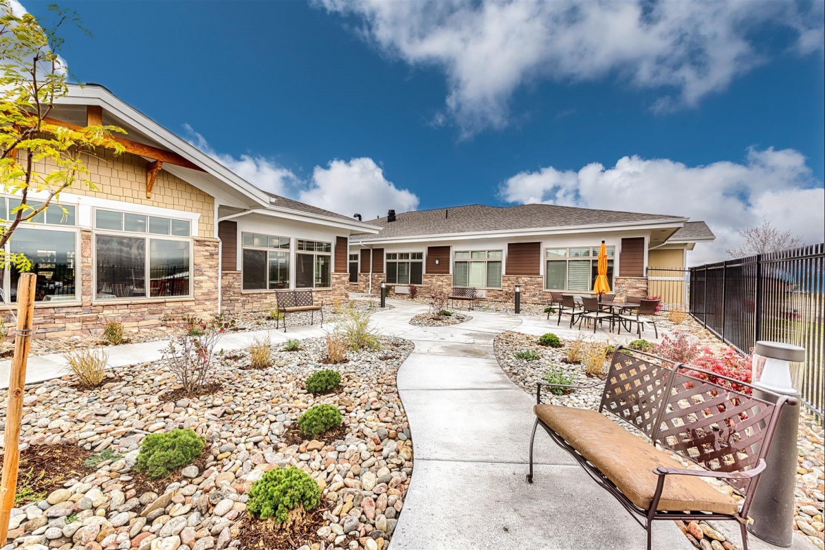 A modern house with a landscaped patio and outdoor seating under a cloudy sky.