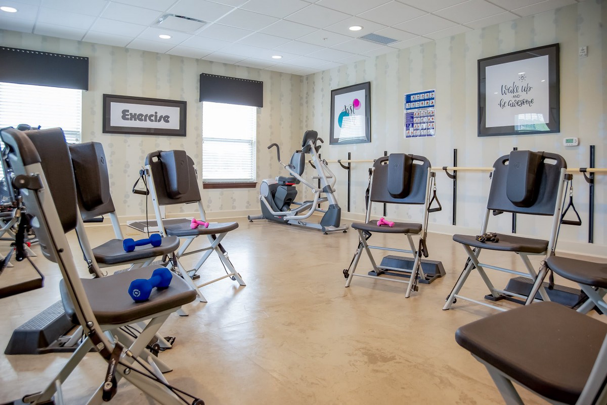 A modern exercise room equipped with chairs, weights, and workout machines.