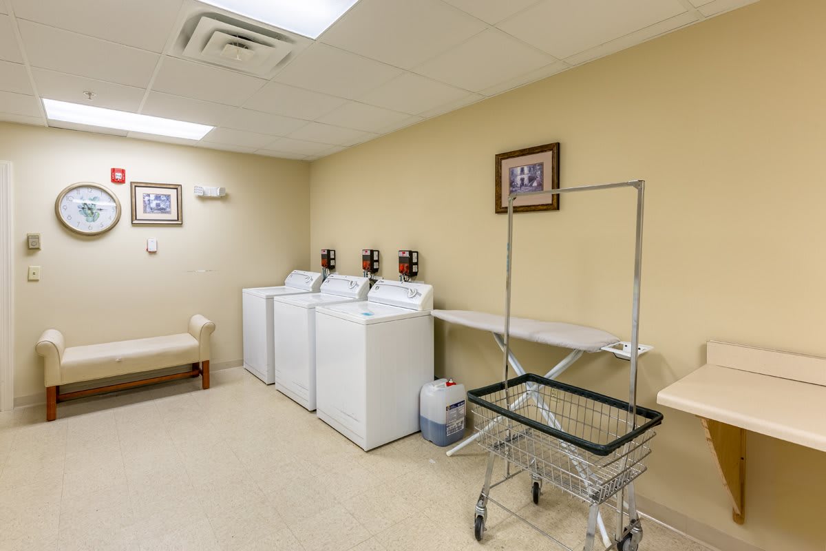A clean and organized laundry room with washing machines, a dryer, and a laundry cart.
