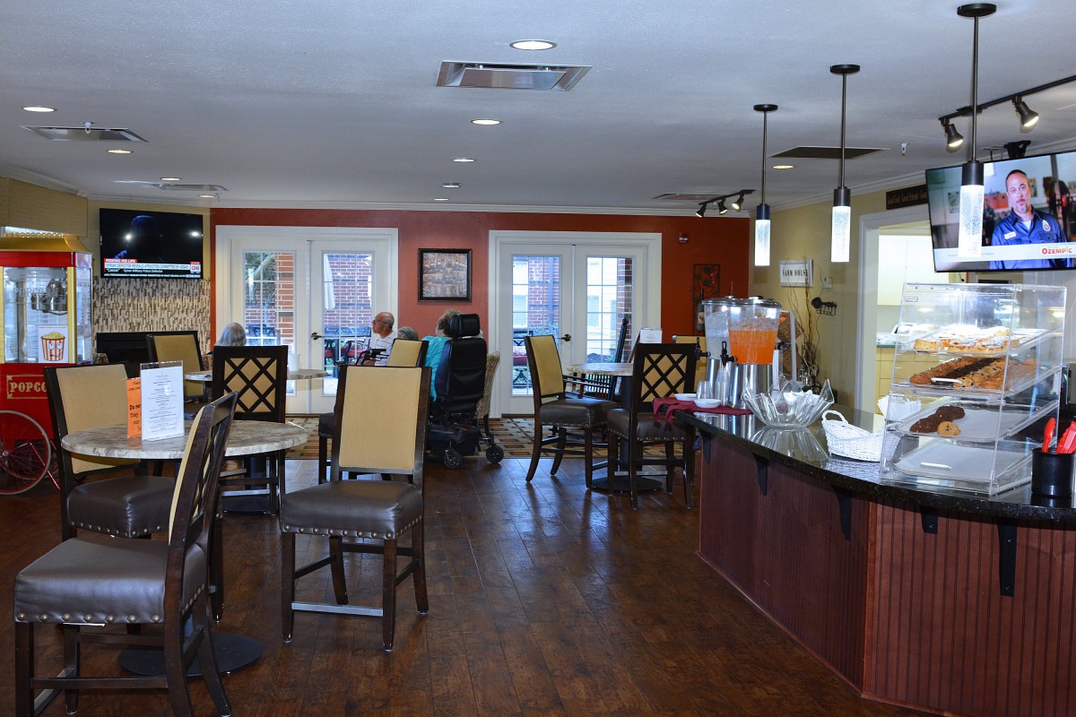 A modern dining area with tables, chairs, and a counter in a warm setting.