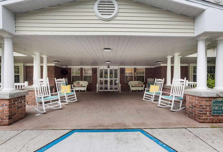 A covered porch with white rocking chairs and outdoor seating.