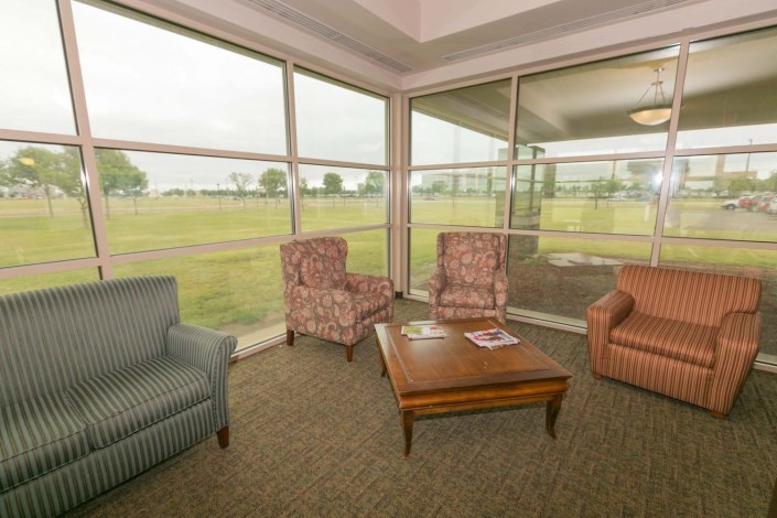 A cozy lounge area with comfortable chairs and a coffee table, surrounded by large windows letting in natural light.