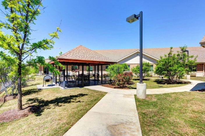 A scenic outdoor area featuring a covered pavilion, surrounded by pathways and landscaping.