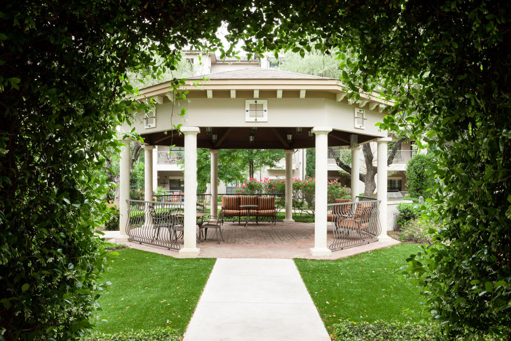 A beautifully landscaped garden featuring a gazebo with lush greenery surrounding it.