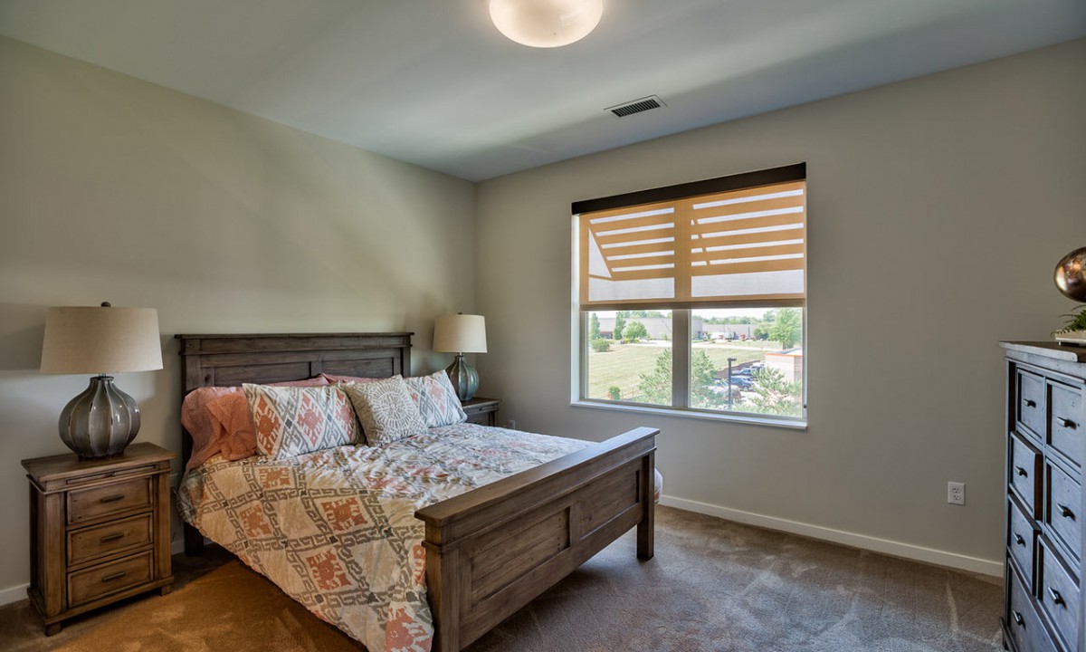 A cozy bedroom with a wooden bed and a large window offering a scenic view.