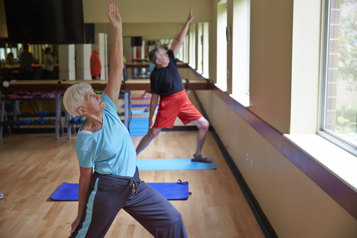 Elderly individuals practicing yoga indoors.