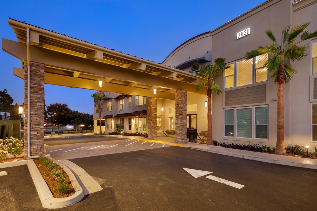 Exterior view of a hotel entrance illuminated during the evening.