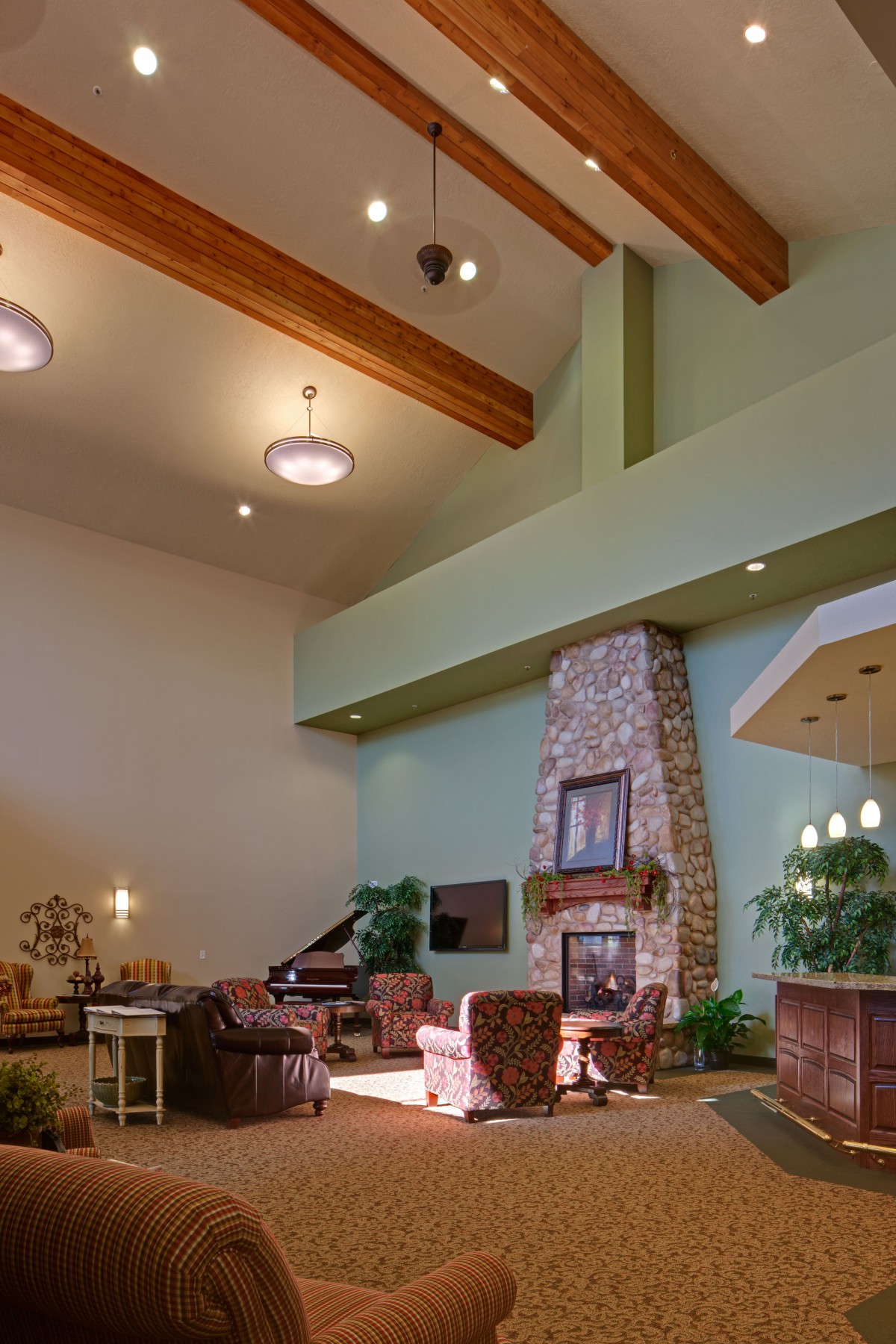 A spacious living room with high ceilings, featuring a stone fireplace, wooden beams, and comfortable seating.
