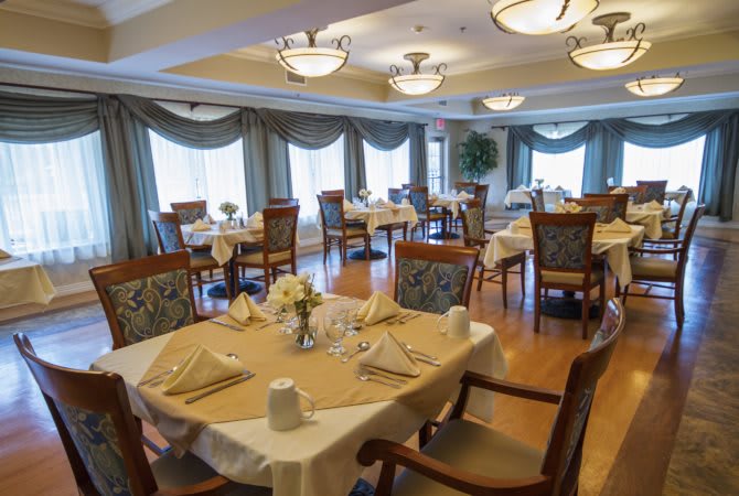 An elegantly set dining room with neatly arranged tables and chairs.