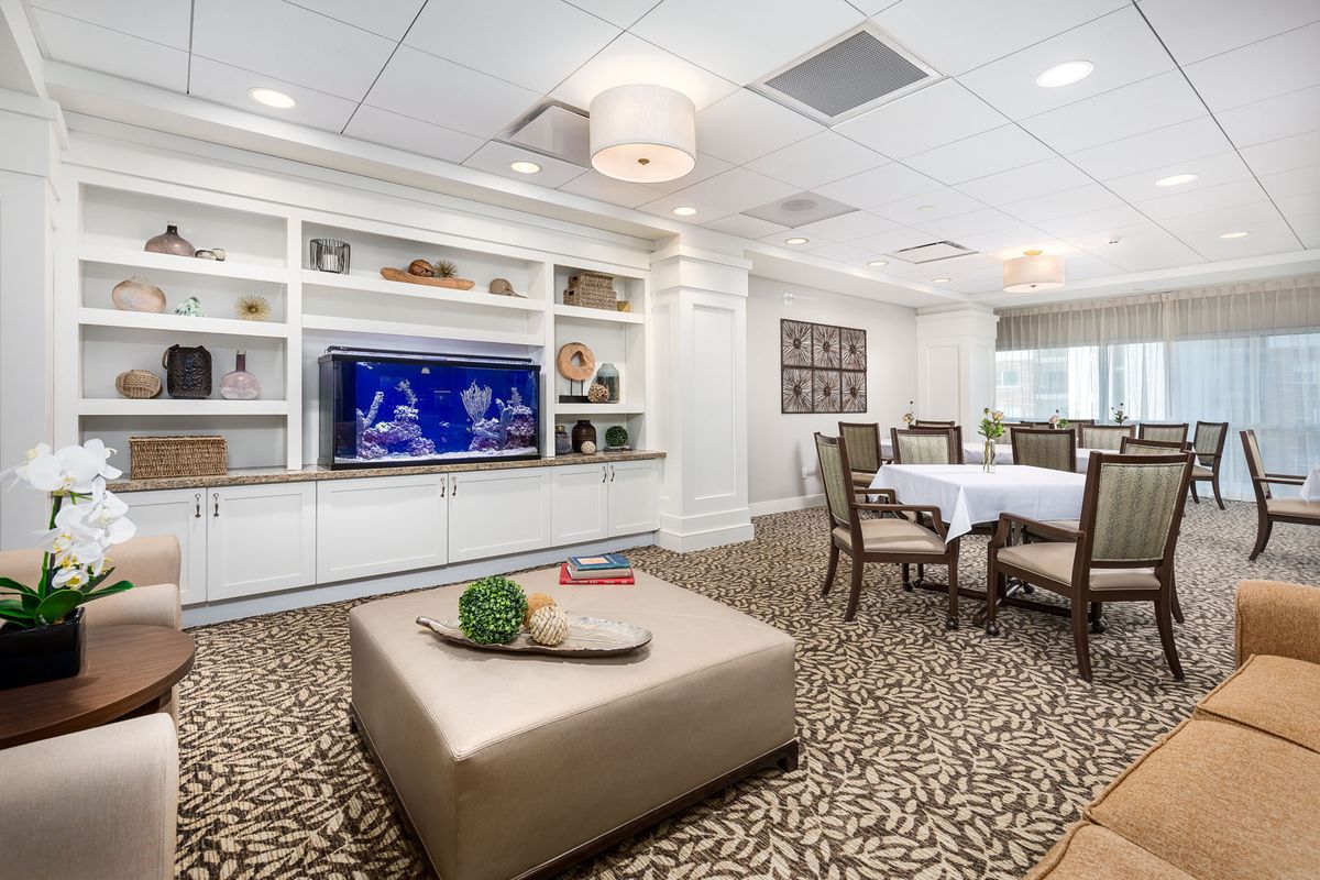 A modern living and dining area featuring a television, bookshelves, and elegant decor.