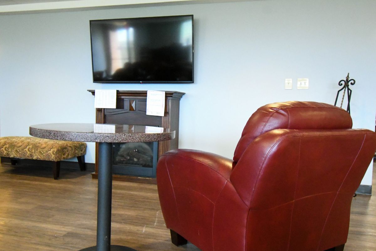 A modern living room with a wall-mounted television and a comfortable red chair.
