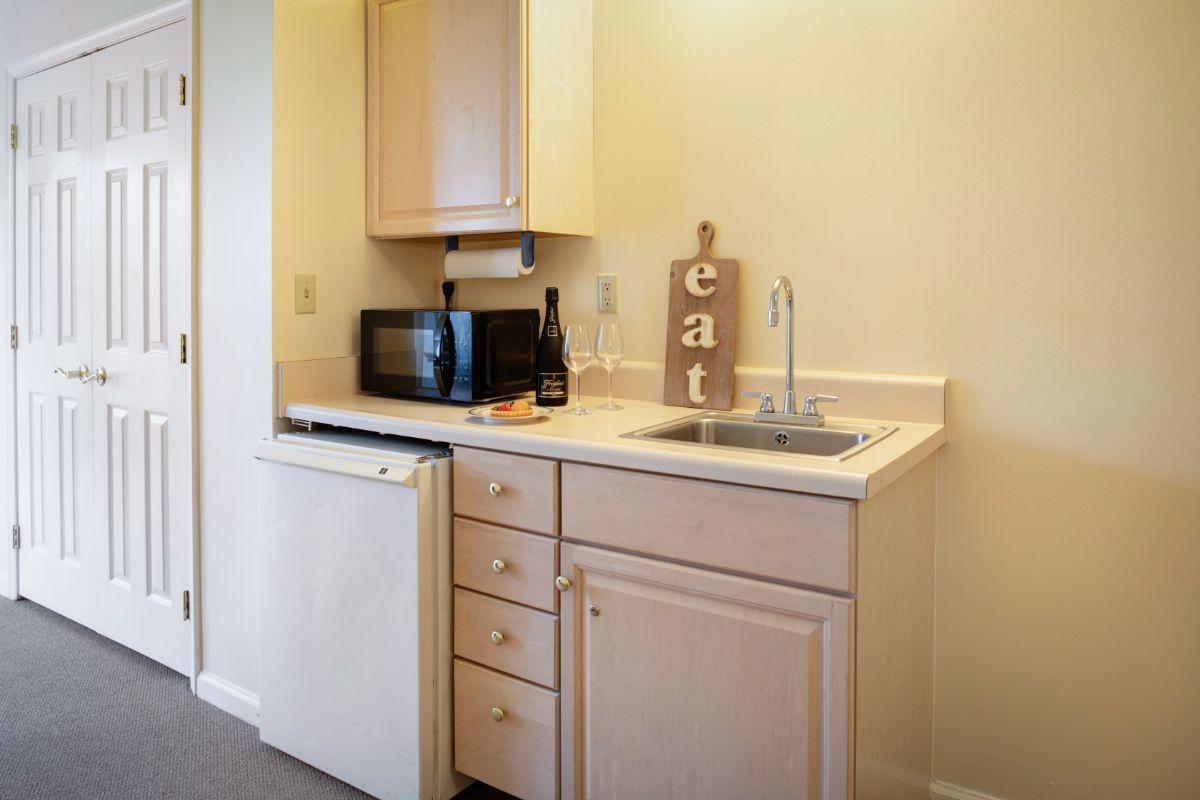 A compact kitchen area with a sink, microwave, and mini fridge.
