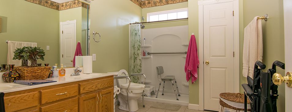 A bathroom with accessibility features, including a shower chair and safety bars.