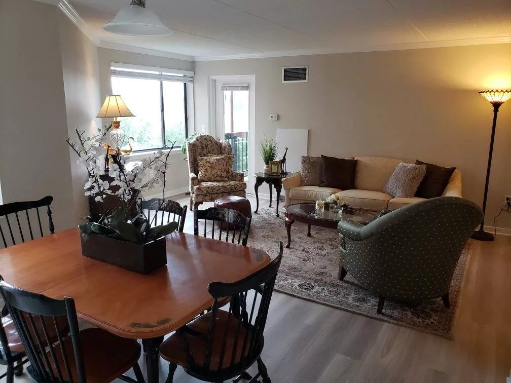 A cozy living room and dining area featuring elegant furniture, a sofa, chairs, and a coffee table.