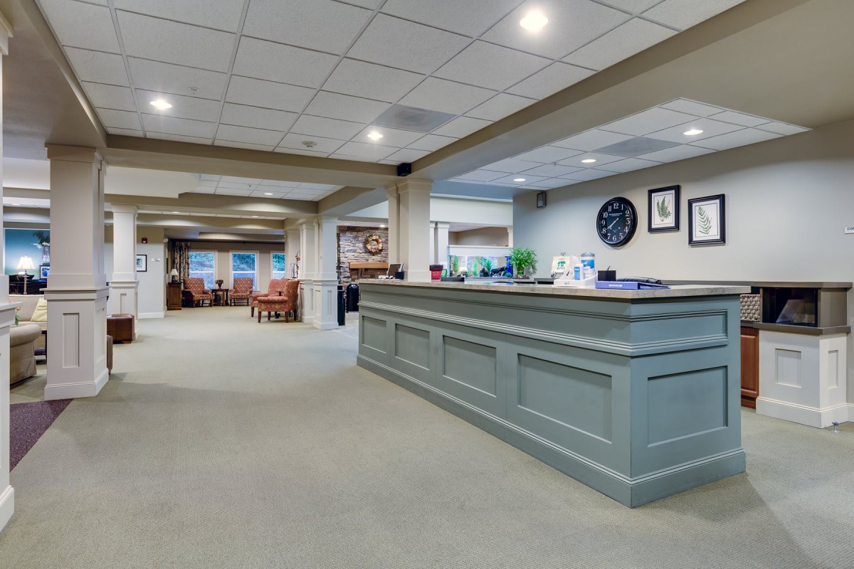 A spacious and well-lit reception area with a large desk and seating in the background.