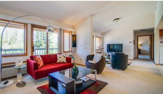 A modern living room with a red sofa, glass coffee table, and large windows.
