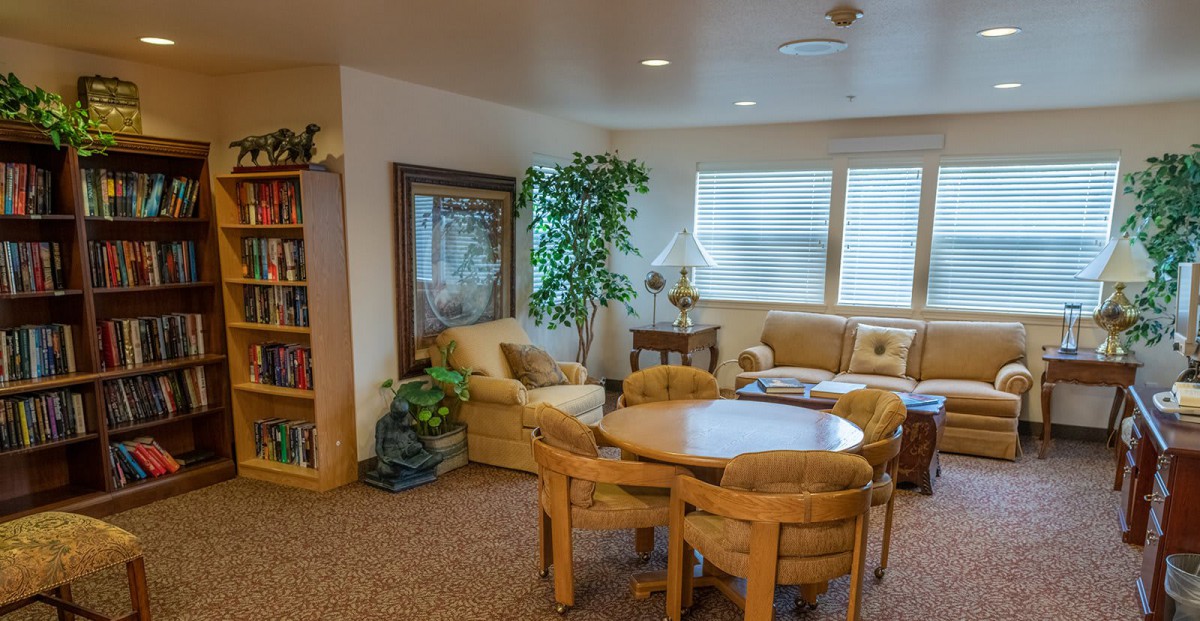 A cozy living room with a seating area, table, chairs, and indoor plants.