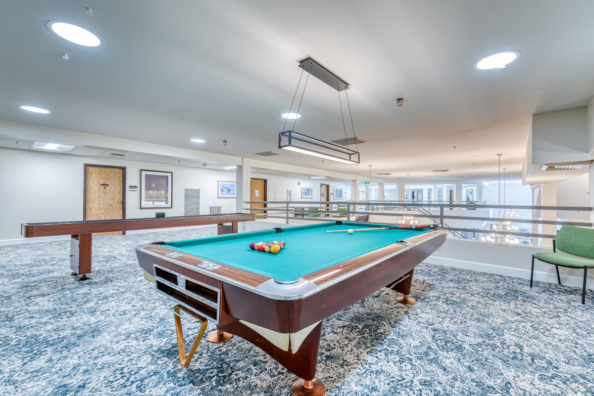 A spacious game room featuring a pool table under bright lighting.
