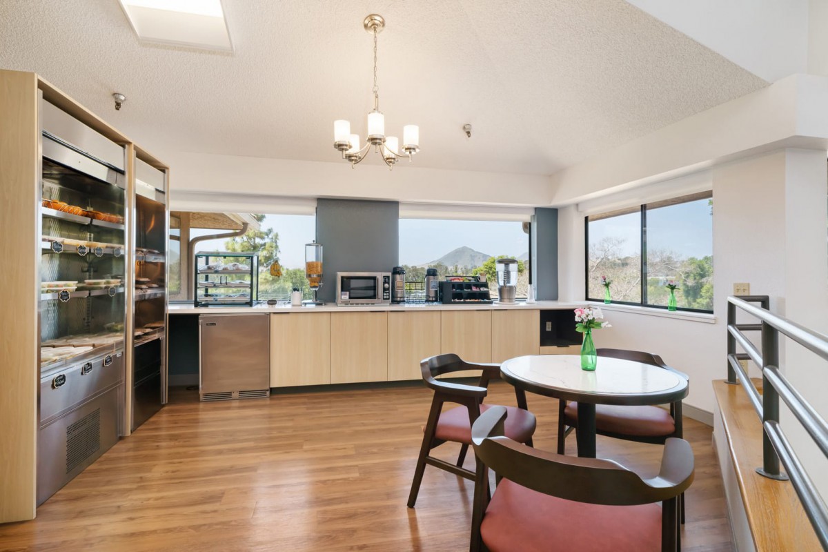 A modern kitchen and dining area with wooden flooring, large windows, and minimalist design.