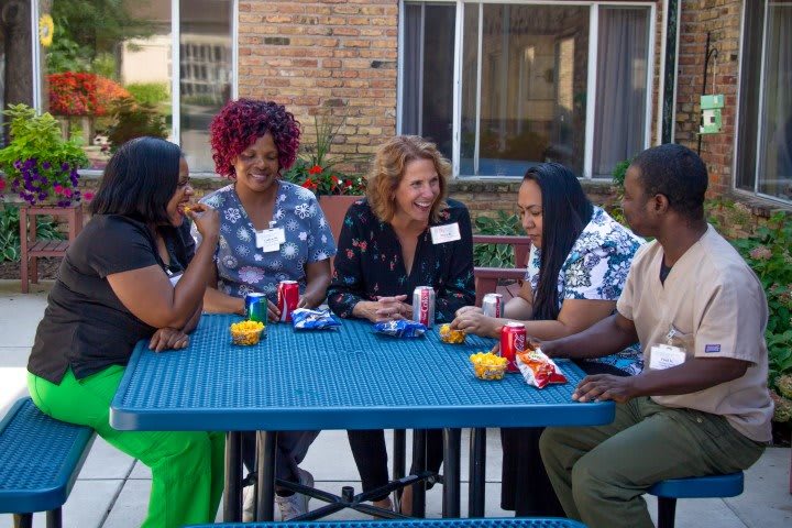 A group of people sitting around a table, enjoying a conversation outdoors.