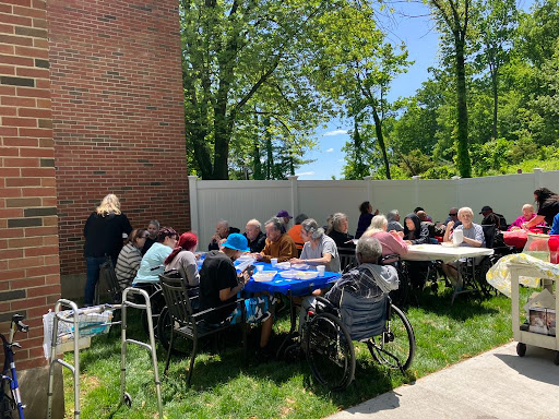 A vibrant outdoor gathering of seniors enjoying a sunny day, engaged in conversation and activities.