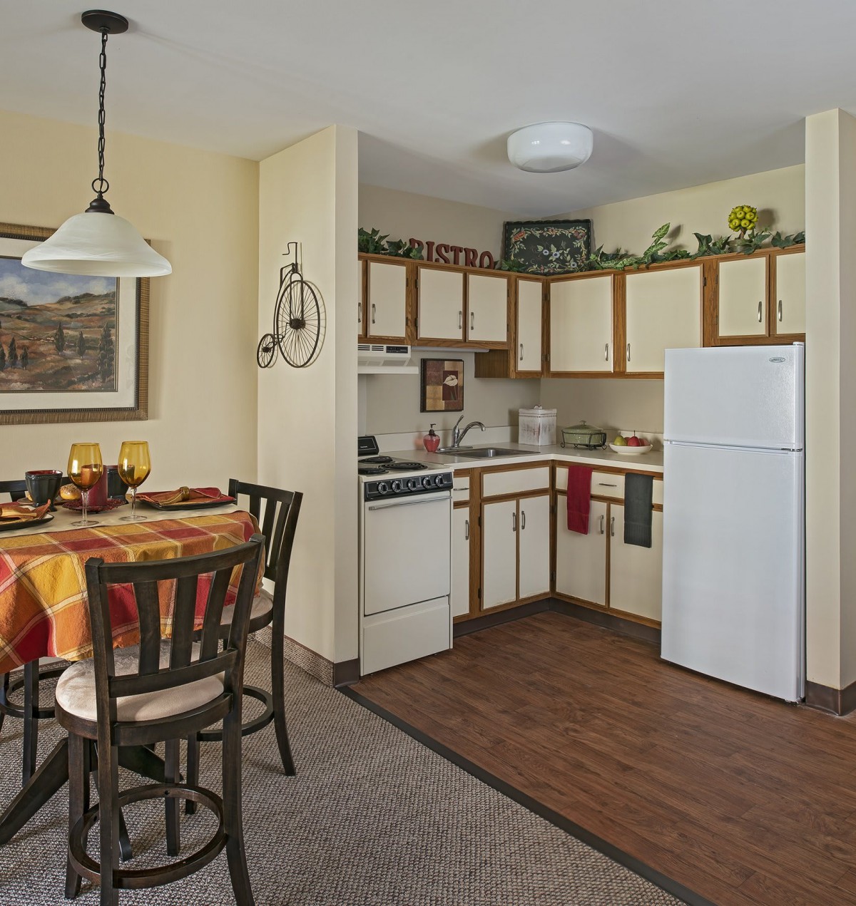 A cozy apartment kitchen with a dining area, featuring a table, chairs, and essential appliances.