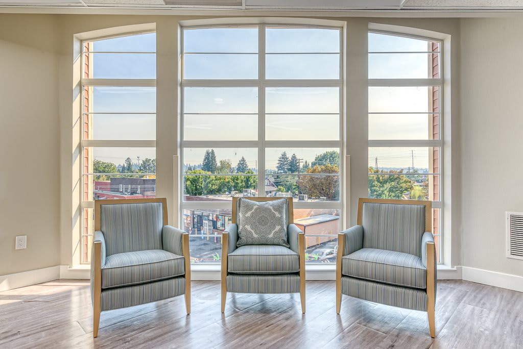 A bright lounge area with modern chairs and large windows offering a scenic view.