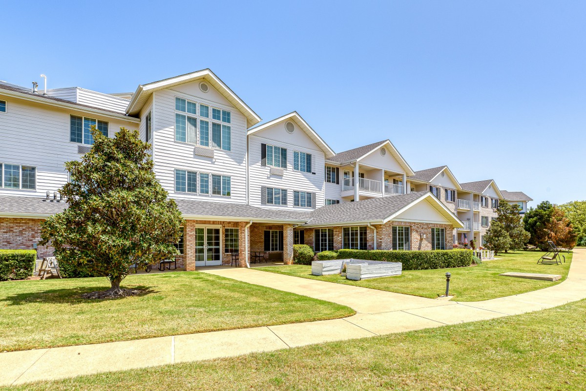 A modern residential apartment complex with well-maintained lawns and a clear blue sky.